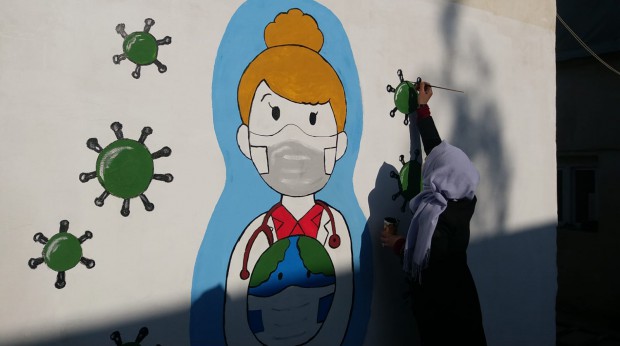 Un membre de l'équipe bleue peint sur les murs d'un orphelinat à Azaz en mars 2021