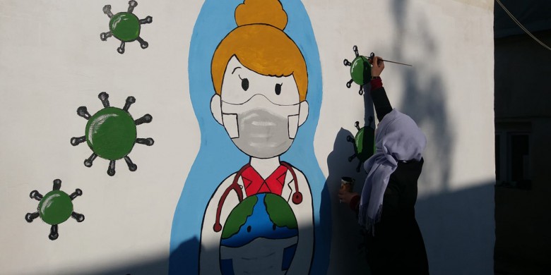Un membre de l'équipe bleue peint sur les murs d'un orphelinat à Azaz en mars 2021